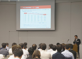9月に行われたシンポジウムで講演する安達氏
